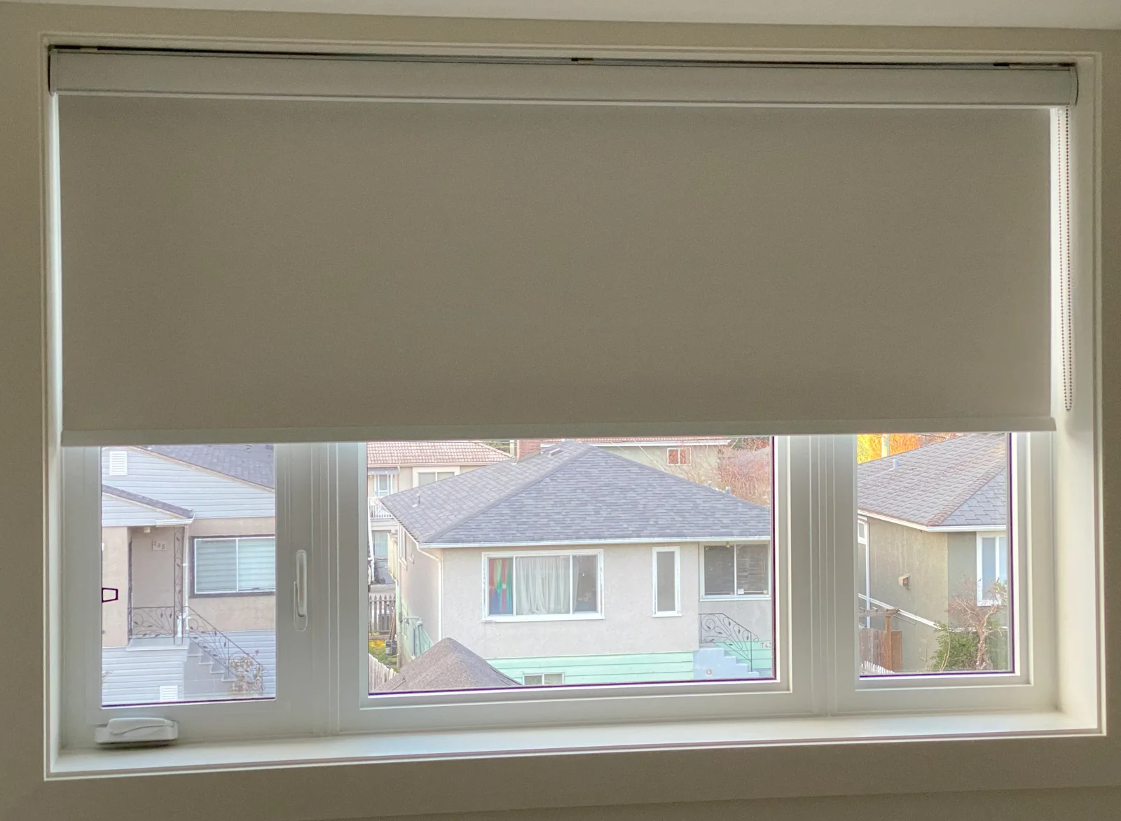 A white roller shade across a wide window